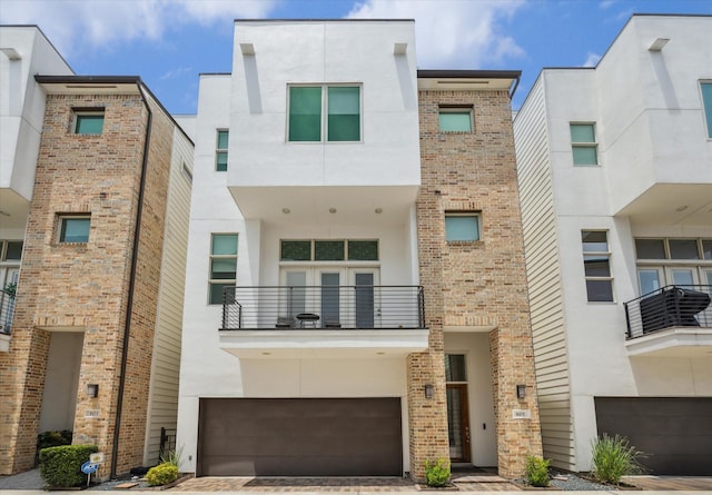 805 Sandman St, Houston, TX 77007 - view of front of property featuring a balcony, an attached garage, stucco siding, and brick siding
