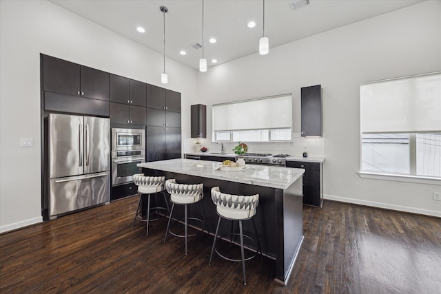 805 Sandman St, Houston, TX 77007 - kitchen with appliances with stainless steel finishes, a kitchen island, a breakfast bar, dark wood-style flooring, and light stone counters