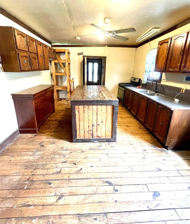 206 E Rogers St, Ganado, TX 77962 - kitchen with stainless steel gas stove, light wood-style floors, a center island, ceiling fan, and ornamental molding