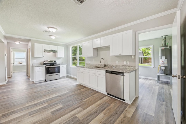 210 Laurel St, Lake Jackson, TX 77566 - kitchen with stainless steel appliances, water heater, under cabinet range hood, white cabinetry, and crown molding