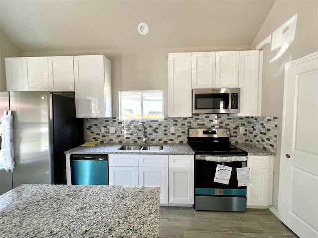 16897 W Alderson, Montgomery, TX 77316 - kitchen with stainless steel appliances, white cabinetry, light stone counters, vaulted ceiling, and recessed lighting