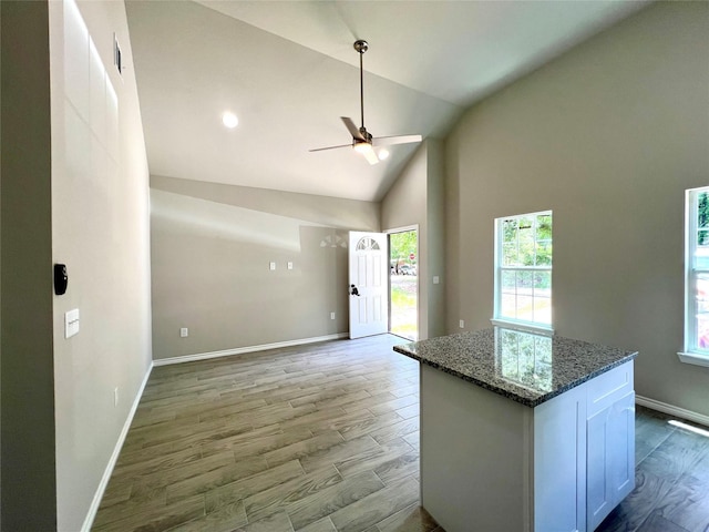 16897 W Alderson, Montgomery, TX 77316 - kitchen featuring a ceiling fan, light wood-style flooring, dark stone countertops, open floor plan, and high vaulted ceiling