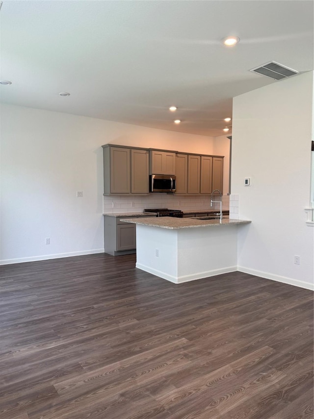 214 Fulton Station Dr, Houston, TX 77009 - kitchen with stainless steel microwave, gray cabinetry, dark wood-style flooring, a peninsula, and decorative backsplash
