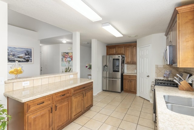 14903 Sugar Sweet Dr, Sugar Land, TX 77498 - kitchen with appliances with stainless steel finishes, decorative backsplash, light tile patterned floors, and brown cabinetry