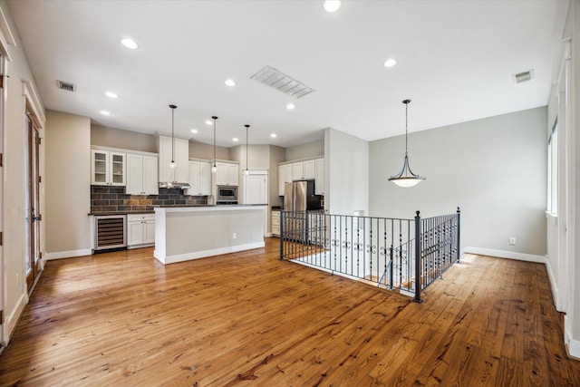 431 Jackson Hill St, Houston, TX 77007 - kitchen with stainless steel appliances, beverage cooler, light wood-type flooring, white cabinetry, and decorative backsplash