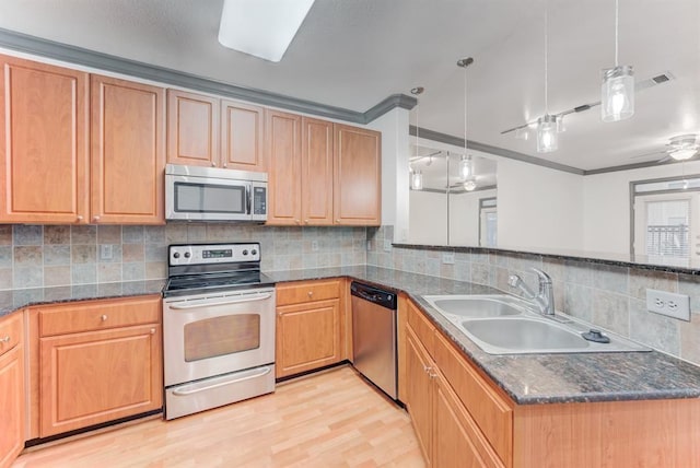 1711 Old Spanish Trl Unit 110, Houston, TX 77054 - kitchen featuring appliances with stainless steel finishes, light wood-style floors, a peninsula, tasteful backsplash, and hanging light fixtures