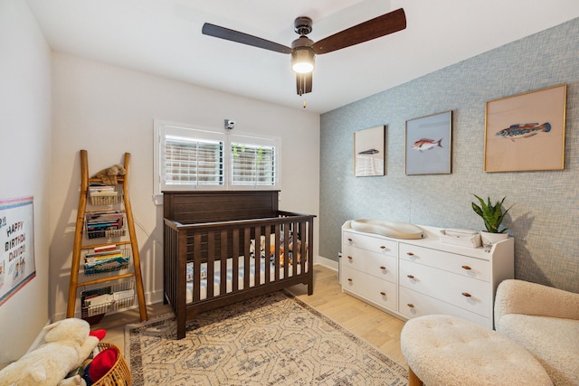 2022 Chaparral Dr, Houston, TX 77043 - bedroom with light wood-type flooring, a crib, and a ceiling fan