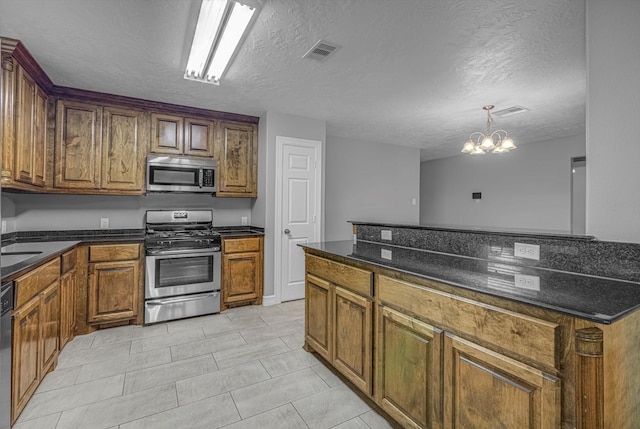 2440 Olympia Dr, West Columbia, TX 77486 - kitchen with stainless steel appliances, a chandelier, a textured ceiling, brown cabinets, and light tile patterned floors
