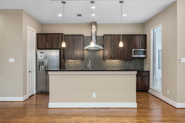 1801 Radcliffe St, Houston, TX 77007 - kitchen with stainless steel appliances, wall chimney exhaust hood, dark brown cabinetry, dark wood-style flooring, and a center island with sink
