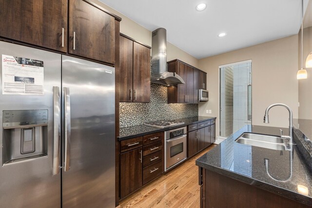 1801 Radcliffe St, Houston, TX 77007 - kitchen with appliances with stainless steel finishes, wall chimney range hood, dark brown cabinets, light wood finished floors, and tasteful backsplash