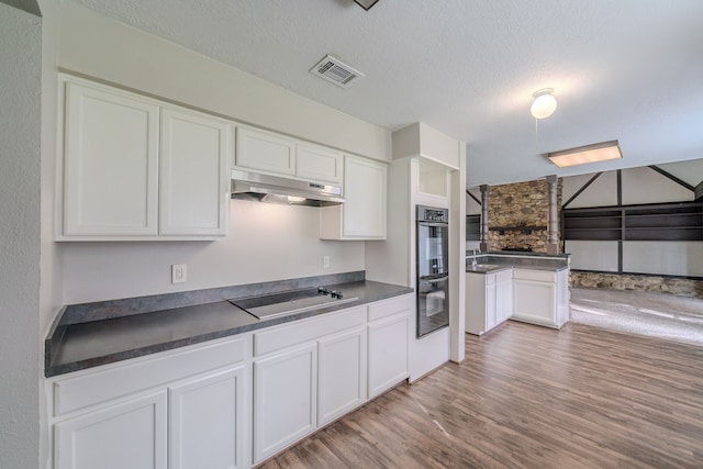 463 Dover Ln, Spring, TX 77373 - kitchen with under cabinet range hood, black appliances, light wood-style floors, dark countertops, and white cabinetry