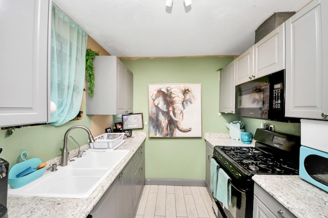 4827 Dalmatian Dr, Houston, TX 77045 - kitchen with black appliances, light wood finished floors, and gray cabinetry