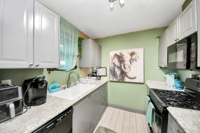 4827 Dalmatian Dr, Houston, TX 77045 - kitchen with black appliances, light wood-style floors, white cabinets, and gray cabinets
