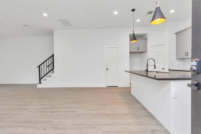 2213 Lee St, Houston, TX 77026 - kitchen with dark countertops, light wood-type flooring, gray cabinetry, open floor plan, and hanging light fixtures