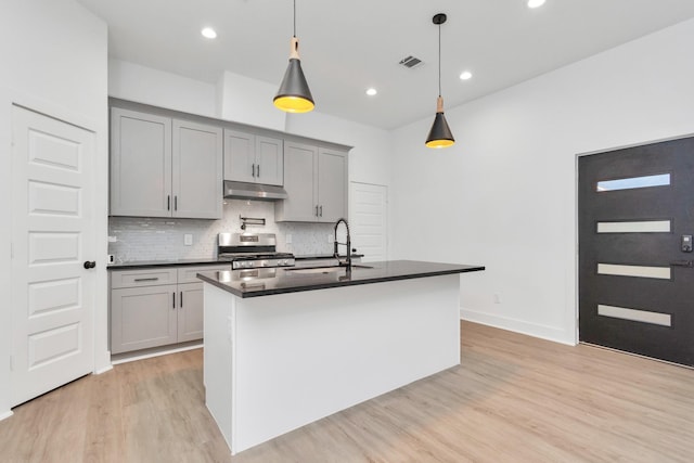 2213 Lee St, Houston, TX 77026 - kitchen featuring dark countertops, gas range, under cabinet range hood, gray cabinets, and light wood finished floors