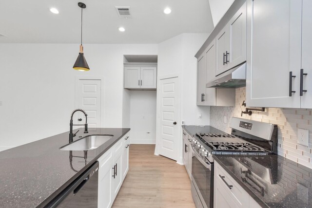 2213 Lee St, Houston, TX 77026 - kitchen featuring stainless steel gas range oven, under cabinet range hood, dishwasher, dark stone countertops, and tasteful backsplash