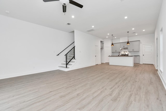 2213 Lee St, Houston, TX 77026 - unfurnished living room featuring ceiling fan, recessed lighting, stairway, and light wood-style floors