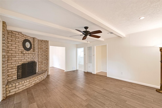 9306 Claridge Dr, Houston, TX 77031 - unfurnished living room featuring a brick fireplace, beam ceiling, wood finished floors, ceiling fan, and a textured ceiling