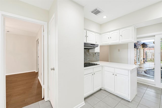 9306 Claridge Dr, Houston, TX 77031 - kitchen with black electric cooktop, under cabinet range hood, white cabinetry, light countertops, and a peninsula