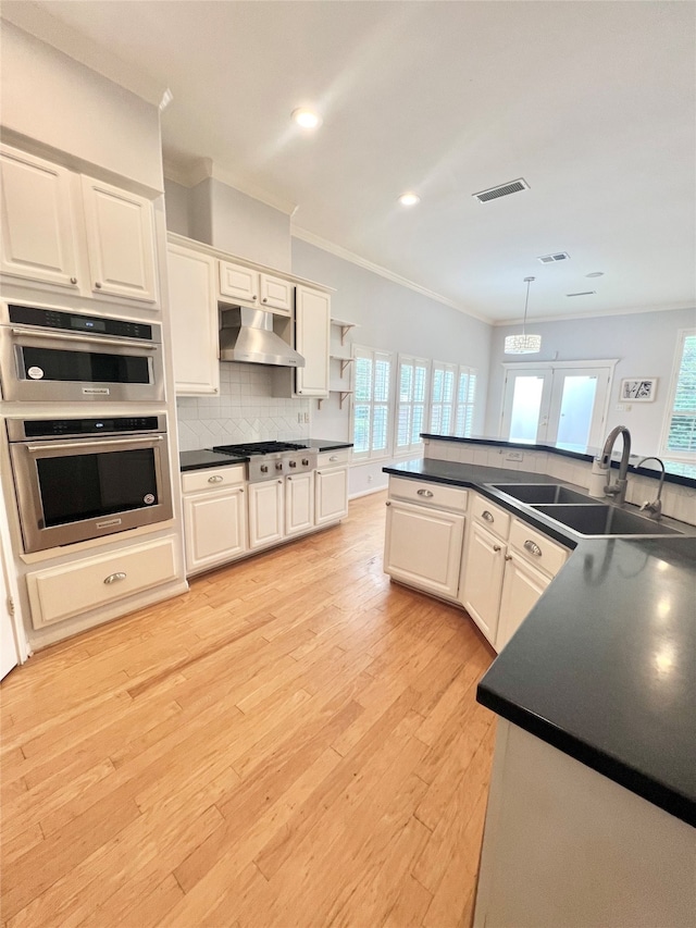 1150 Sienna Hill Dr, Houston, TX 77077 - kitchen with under cabinet range hood, dark countertops, ornamental molding, stainless steel gas stovetop, and french doors