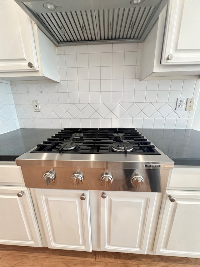 1150 Sienna Hill Dr, Houston, TX 77077 - kitchen view of extractor fan, dark countertops, stainless steel gas stovetop, and decorative backsplash