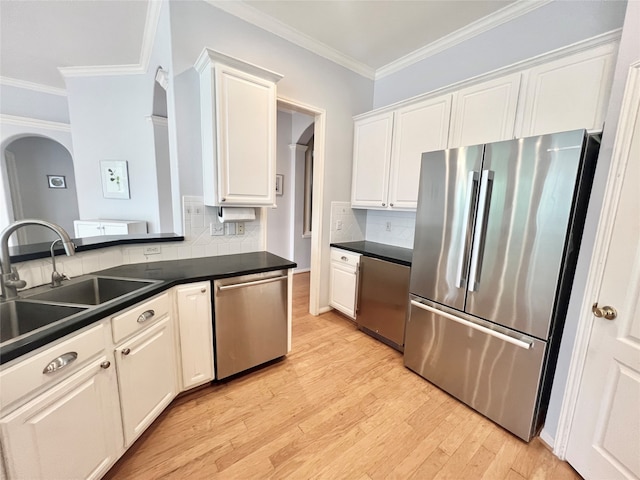 1150 Sienna Hill Dr, Houston, TX 77077 - kitchen with stainless steel appliances, arched walkways, dark countertops, ornamental molding, and light wood-type flooring