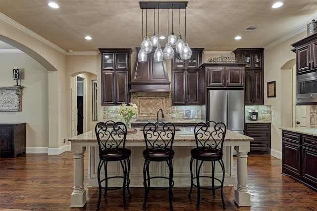9714 Luna Springs Ln, Cypress, TX 77433 - kitchen featuring stainless steel appliances, arched walkways, recessed lighting, a kitchen bar, and glass insert cabinets