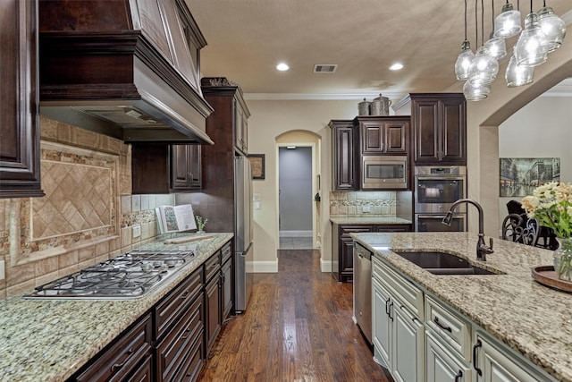 9714 Luna Springs Ln, Cypress, TX 77433 - kitchen with stainless steel appliances, arched walkways, custom range hood, dark brown cabinetry, and ornamental molding