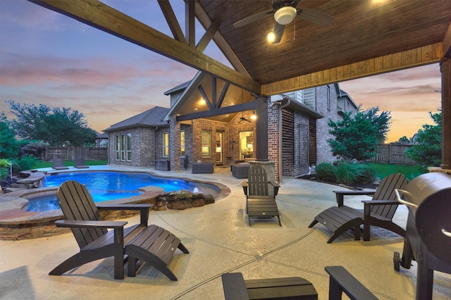 9714 Luna Springs Ln, Cypress, TX 77433 - pool at dusk featuring ceiling fan, area for grilling, a fenced backyard, and an in-ground hot tub