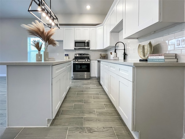 4817 Keeland St, Houston, TX 77016 - kitchen with appliances with stainless steel finishes, tasteful backsplash, recessed lighting, white cabinetry, and hanging light fixtures