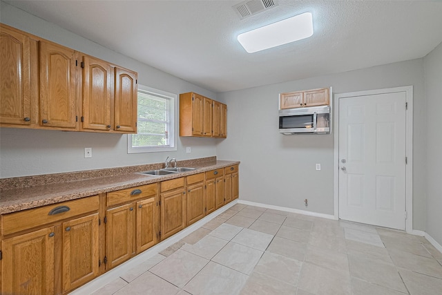 3024 Brackenridge St, Houston, TX 77026 - kitchen featuring stainless steel microwave, brown cabinets, and light tile patterned floors