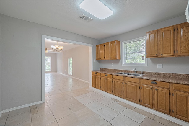 3024 Brackenridge St, Houston, TX 77026 - kitchen with a chandelier, plenty of natural light, light tile patterned floors, and brown cabinetry