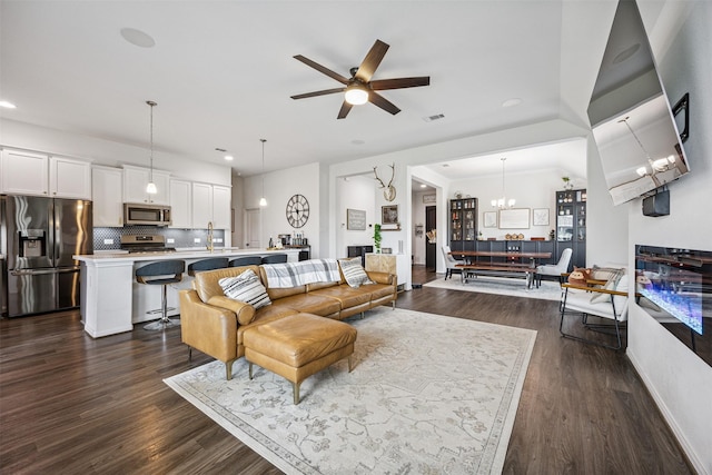 15603 Beltie Dr, Humble, TX 77346 - living room with recessed lighting, dark wood-style flooring, a ceiling fan, a chandelier, and a fireplace