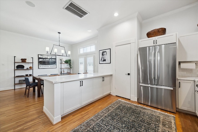 5220 Hazard St, Houston, TX 77098 - kitchen featuring stainless steel refrigerator, a peninsula, ornamental molding, light wood-style flooring, and a chandelier