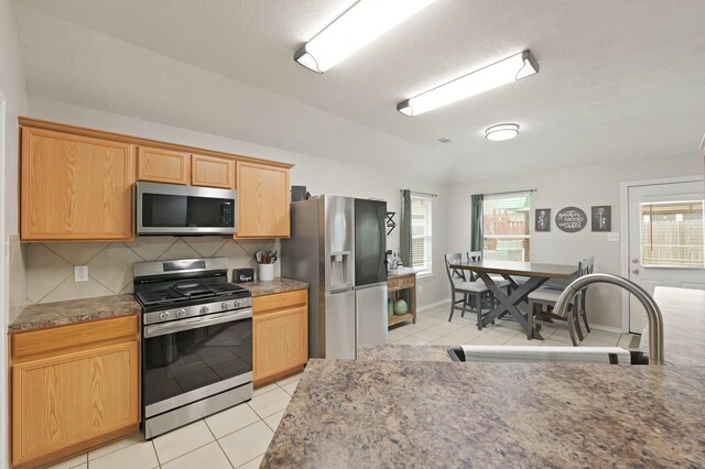 15010 Sunset Villa Ct, Humble, TX 77396 - kitchen with appliances with stainless steel finishes, light tile patterned floors, tasteful backsplash, vaulted ceiling, and light countertops