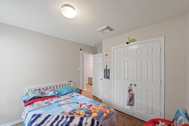 15010 Sunset Villa Ct, Humble, TX 77396 - bedroom with wood finished floors, a closet, and a textured ceiling