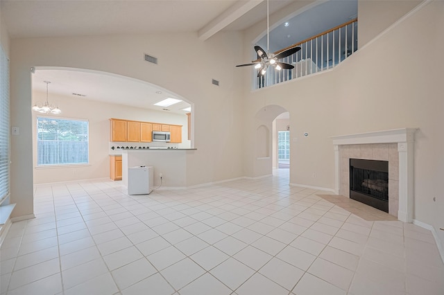 17134 Fairway Glen Ct, Sugar Land, TX 77498 - unfurnished living room with arched walkways, a tiled fireplace, ceiling fan, light tile patterned floors, and beamed ceiling