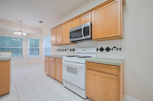 17134 Fairway Glen Ct, Sugar Land, TX 77498 - kitchen with white range with gas cooktop, stainless steel microwave, a chandelier, and decorative backsplash