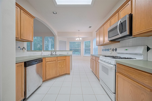 17134 Fairway Glen Ct, Sugar Land, TX 77498 - kitchen with appliances with stainless steel finishes, decorative backsplash, a chandelier, light tile patterned floors, and a peninsula