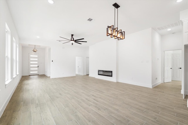 213 N 7th St, La Porte, TX 77571 - unfurnished living room featuring light wood-style flooring, a glass covered fireplace, ceiling fan, recessed lighting, and a chandelier