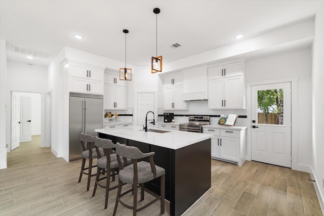 213 N 7th St, La Porte, TX 77571 - kitchen featuring custom exhaust hood, appliances with stainless steel finishes, light wood-type flooring, a breakfast bar area, and recessed lighting