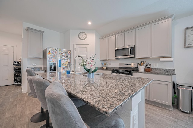 3918 Beltingham Bend Way, Fulshear, TX 77441 - kitchen featuring stainless steel appliances, light stone counters, light wood-type flooring, a kitchen breakfast bar, and recessed lighting