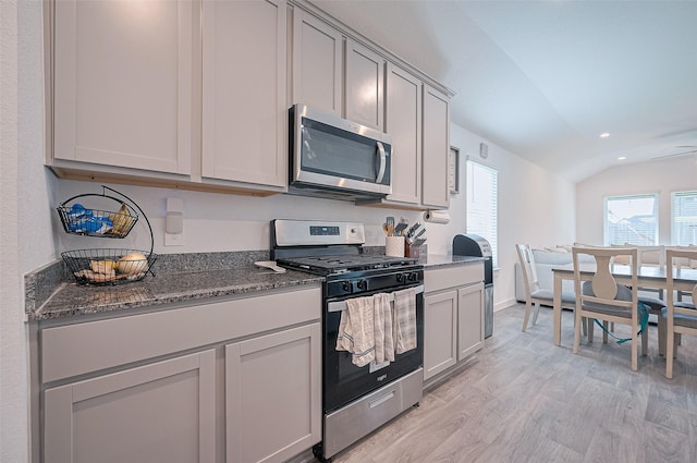 3918 Beltingham Bend Way, Fulshear, TX 77441 - kitchen featuring appliances with stainless steel finishes, light wood-style floors, dark stone counters, lofted ceiling, and recessed lighting