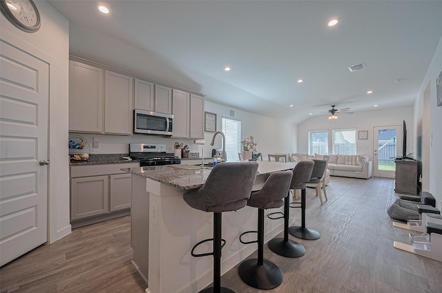 3918 Beltingham Bend Way, Fulshear, TX 77441 - kitchen featuring stainless steel microwave, gas range, gray cabinetry, a kitchen breakfast bar, and recessed lighting