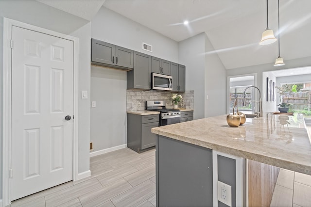 16310 Mulberry Run Ct, Sugar Land, TX 77498 - kitchen featuring stainless steel appliances, gray cabinetry, decorative backsplash, decorative light fixtures, and light stone counters