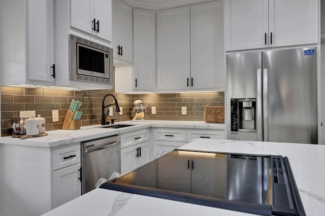 6202 Oleander Dr, Baytown, TX 77523 - kitchen featuring stainless steel appliances, white cabinets, decorative backsplash, and light stone counters