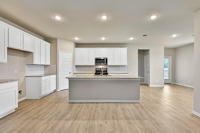 160 Majestic Shores Ln, La Porte, TX 77571 - kitchen featuring stainless steel microwave, decorative backsplash, light wood finished floors, white cabinetry, and recessed lighting