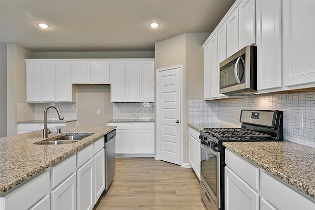 160 Majestic Shores Ln, La Porte, TX 77571 - kitchen with appliances with stainless steel finishes, light wood-type flooring, white cabinets, decorative backsplash, and recessed lighting