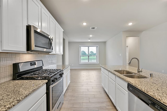 160 Majestic Shores Ln, La Porte, TX 77571 - kitchen featuring appliances with stainless steel finishes, decorative backsplash, white cabinetry, light stone counters, and recessed lighting