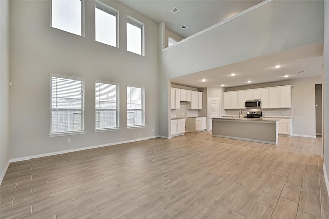160 Majestic Shores Ln, La Porte, TX 77571 - unfurnished living room with light wood-style floors, a high ceiling, and recessed lighting